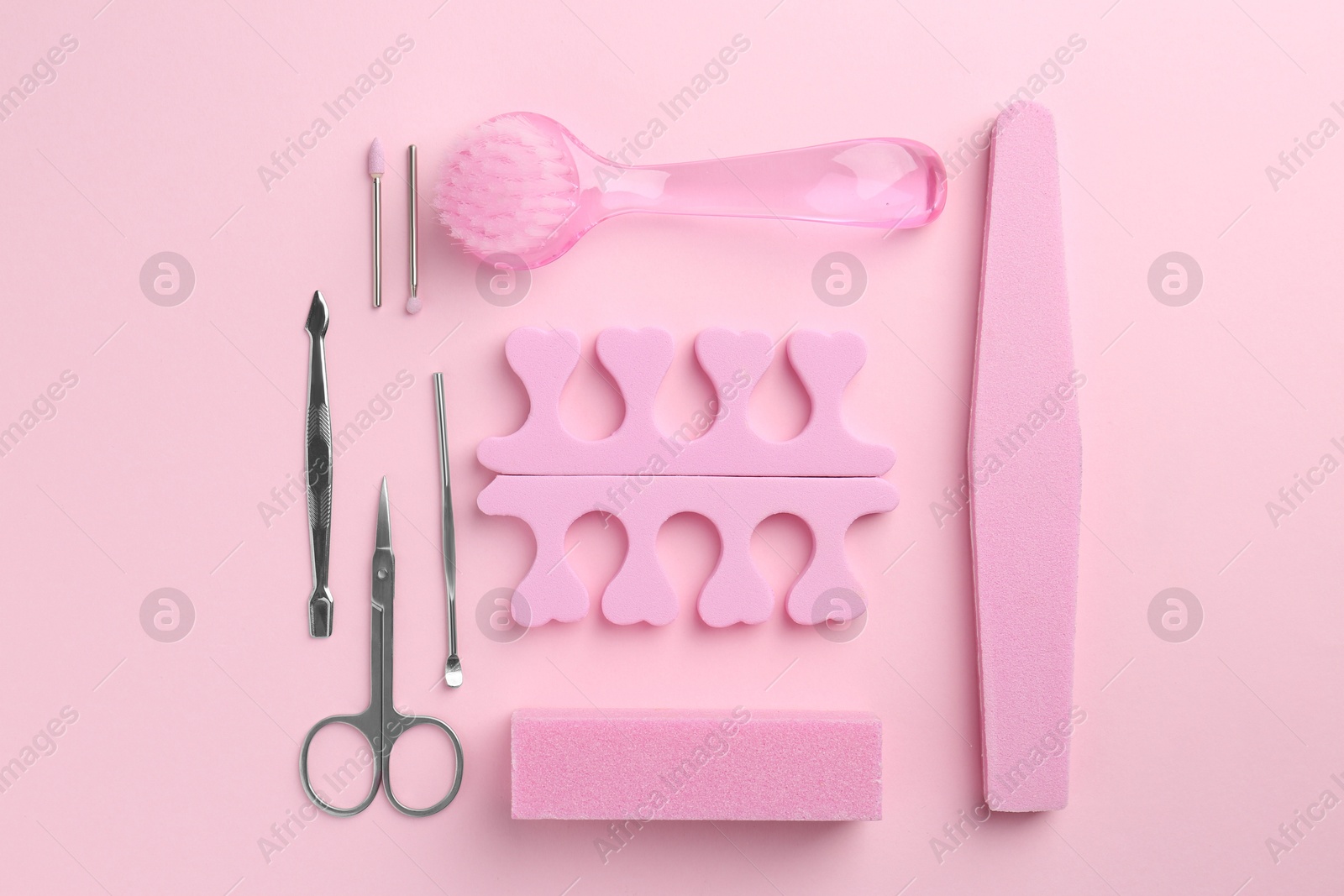 Photo of Set of pedicure tools on pink background, flat lay