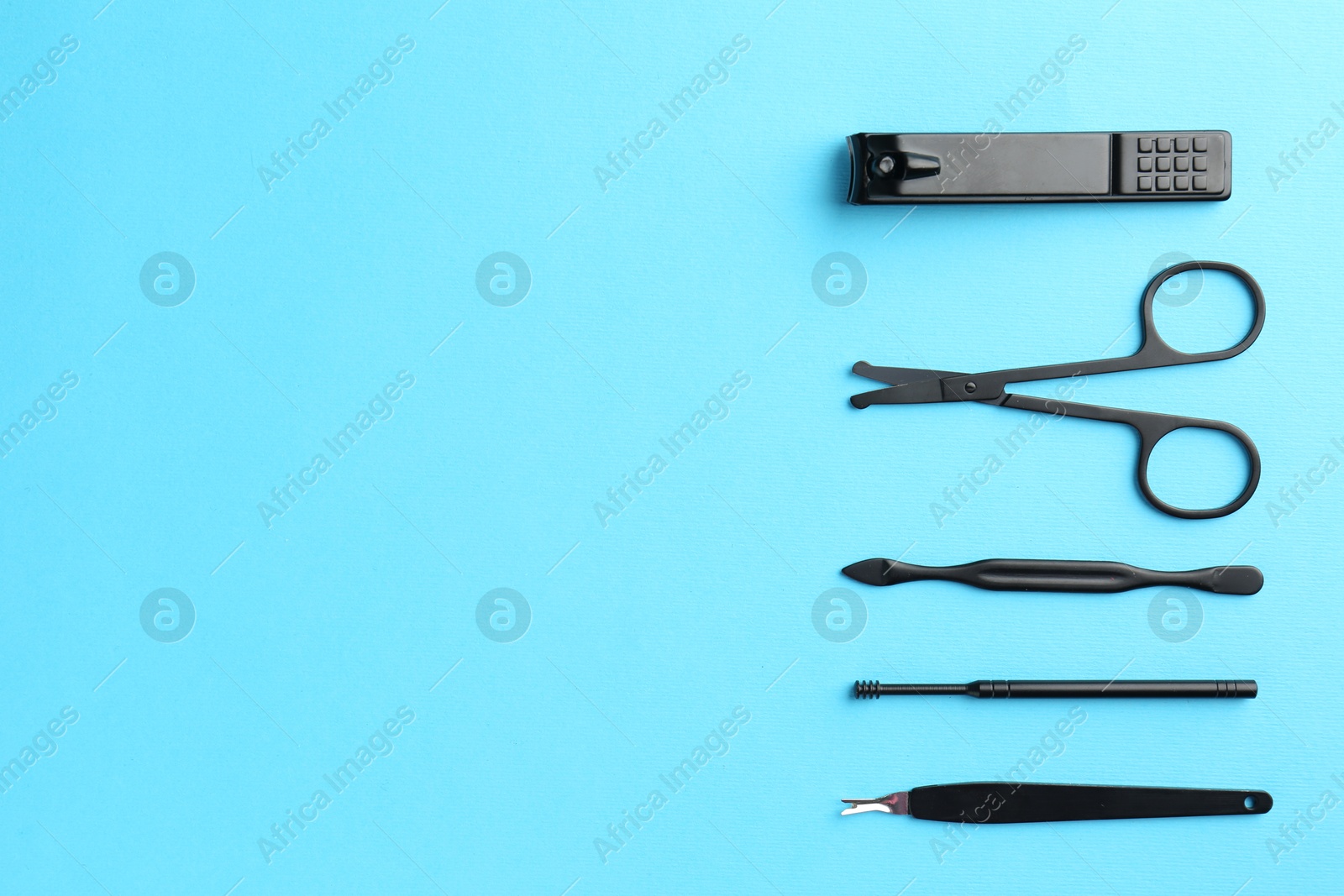 Photo of Set of pedicure tools on light blue background, flat lay. Space for text