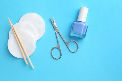 Photo of Pedicure procedure. Nail polish, scissors, orange sticks and cotton pads on light blue background, flat lay