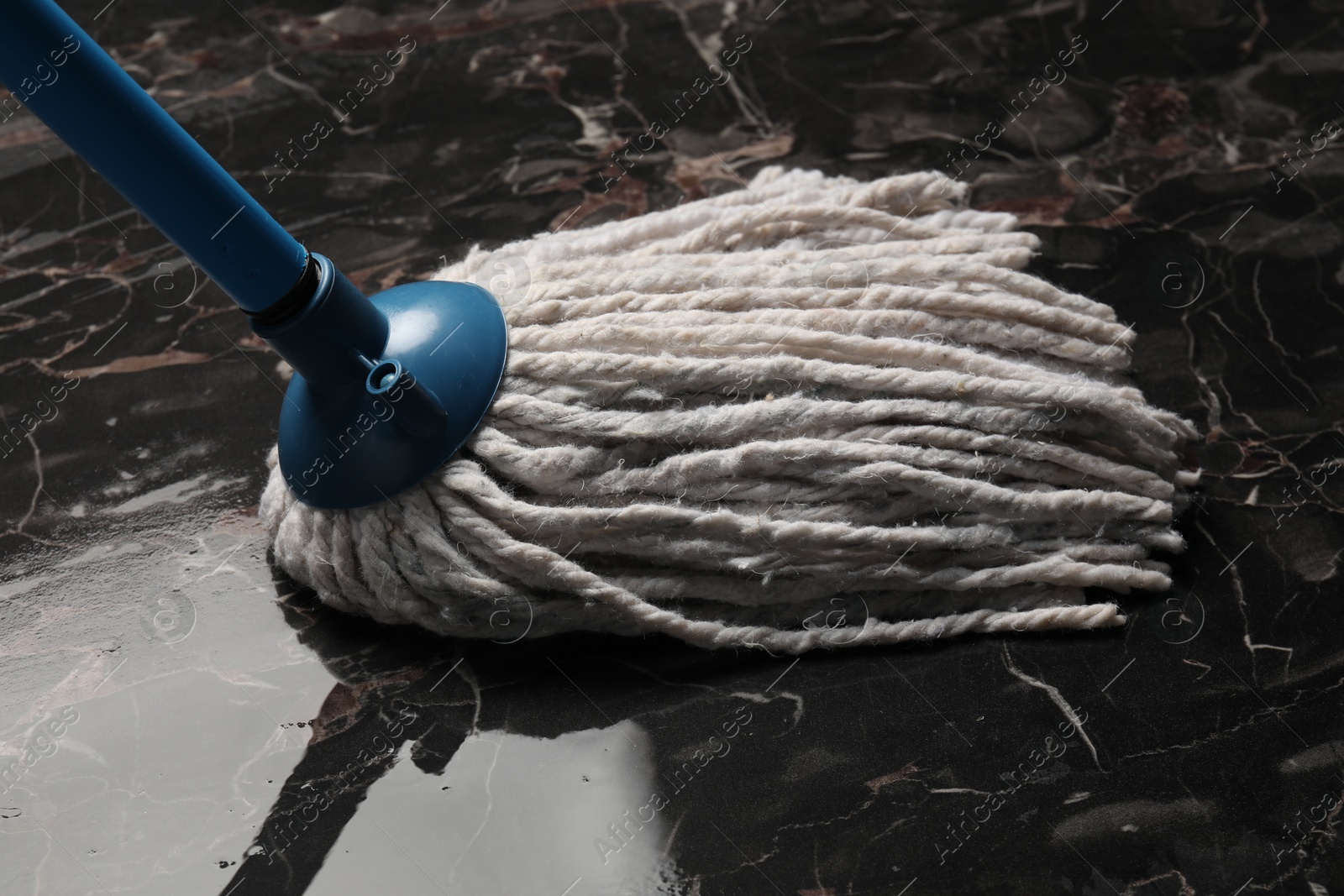 Photo of Cleaning black marble floor with string mop, closeup