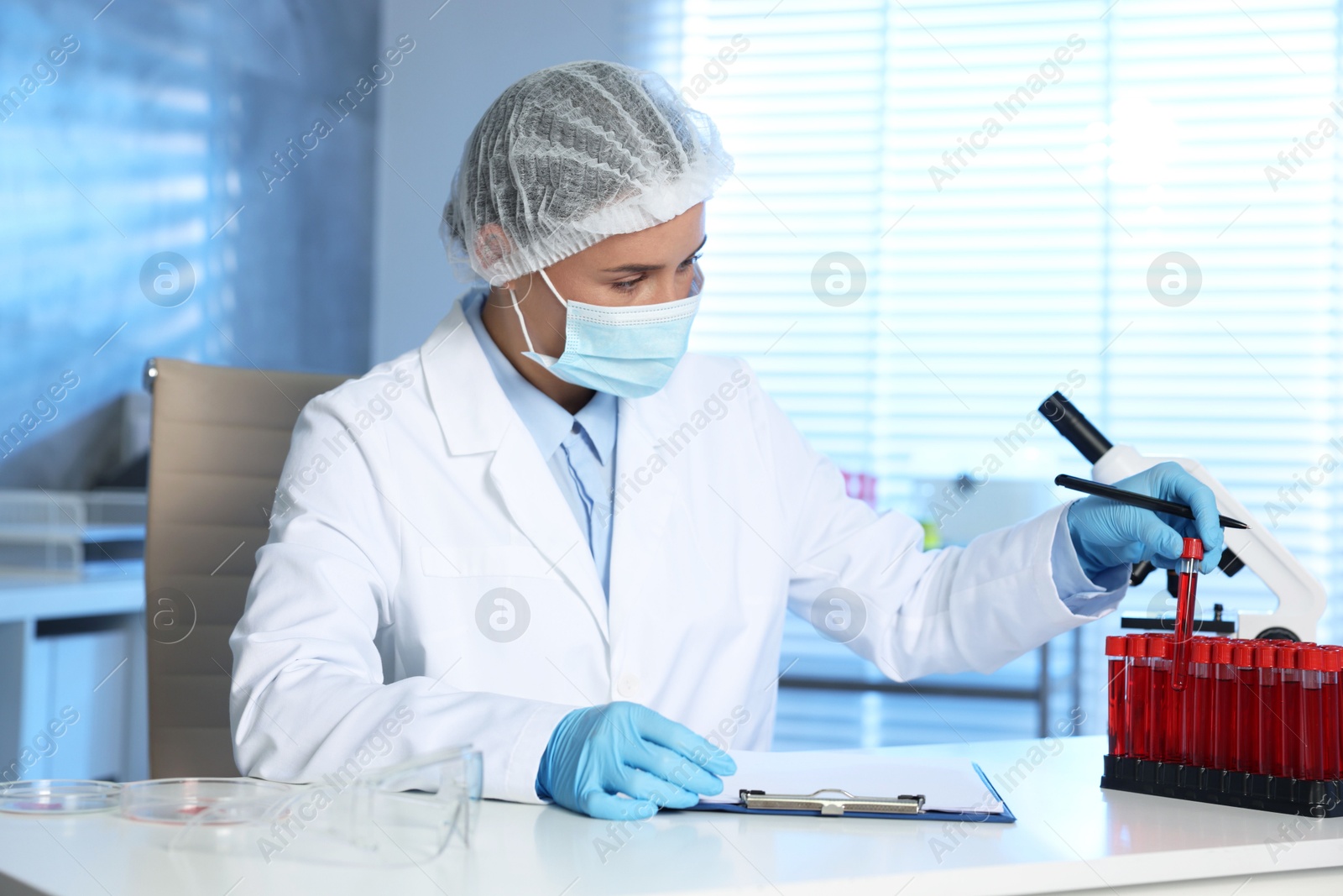 Photo of Laboratory testing. Doctor taking test tube with blood sample at table indoors