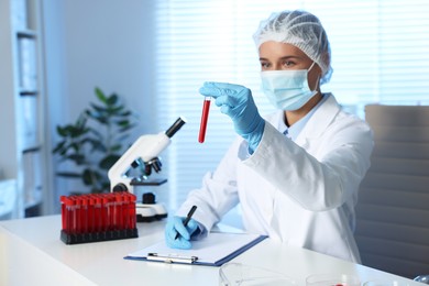 Photo of Laboratory testing. Doctor with blood sample working at table indoors