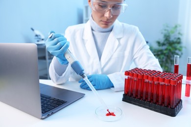 Photo of Laboratory testing. Doctor dripping blood sample into Petri dish at table indoors