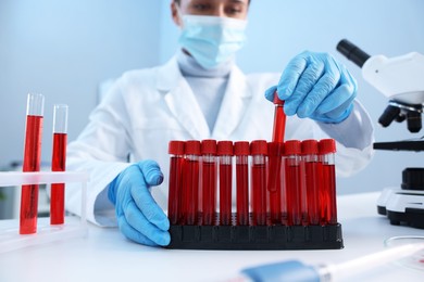 Photo of Laboratory testing. Doctor taking test tube with blood sample at table indoors, selective focus