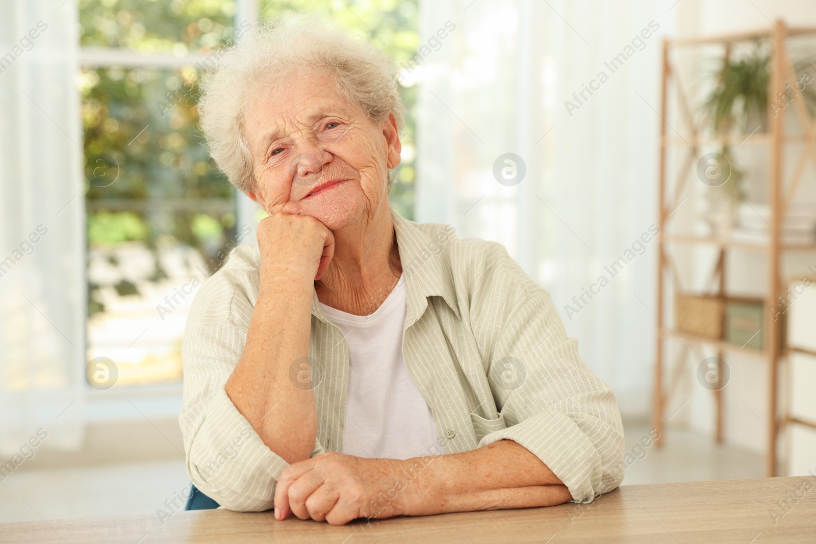 Photo of Portrait of beautiful senior woman at wooden table indoors