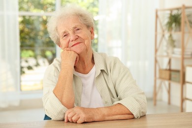 Photo of Portrait of beautiful senior woman at wooden table indoors