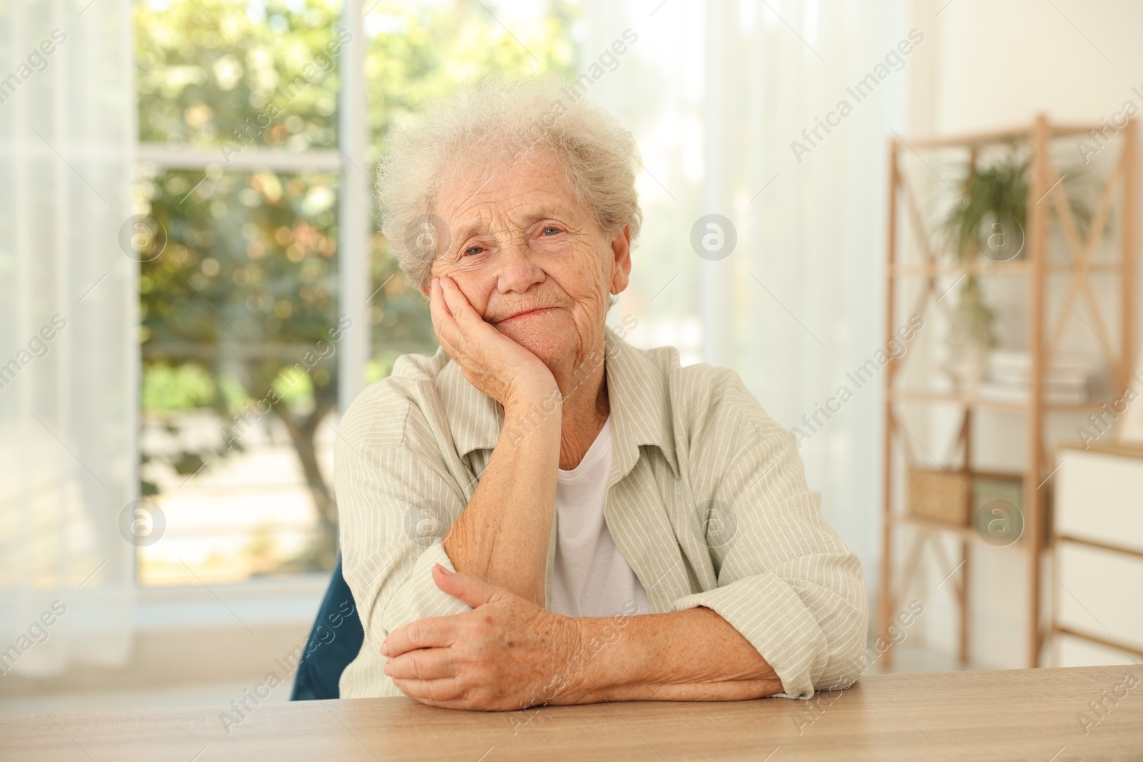 Photo of Portrait of beautiful senior woman at wooden table indoors