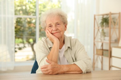 Photo of Portrait of beautiful senior woman at wooden table indoors