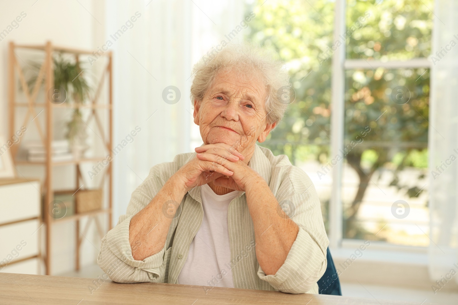 Photo of Portrait of beautiful senior woman at wooden table indoors