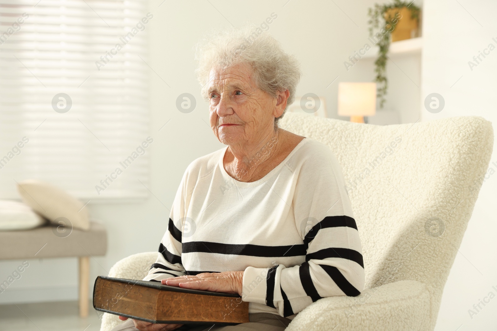 Photo of Senior woman with book sitting on armchair at home