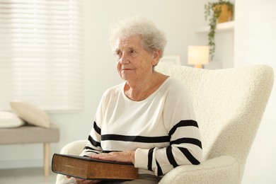 Photo of Senior woman with book sitting on armchair at home