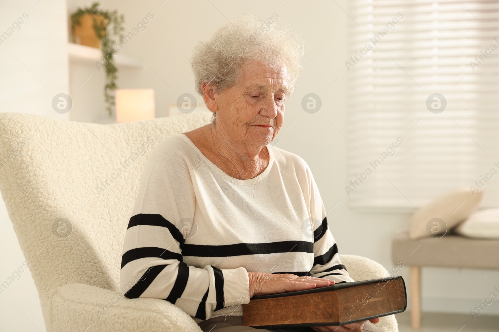 Photo of Senior woman with book sitting on armchair at home