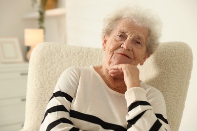 Beautiful senior woman sitting on armchair at home