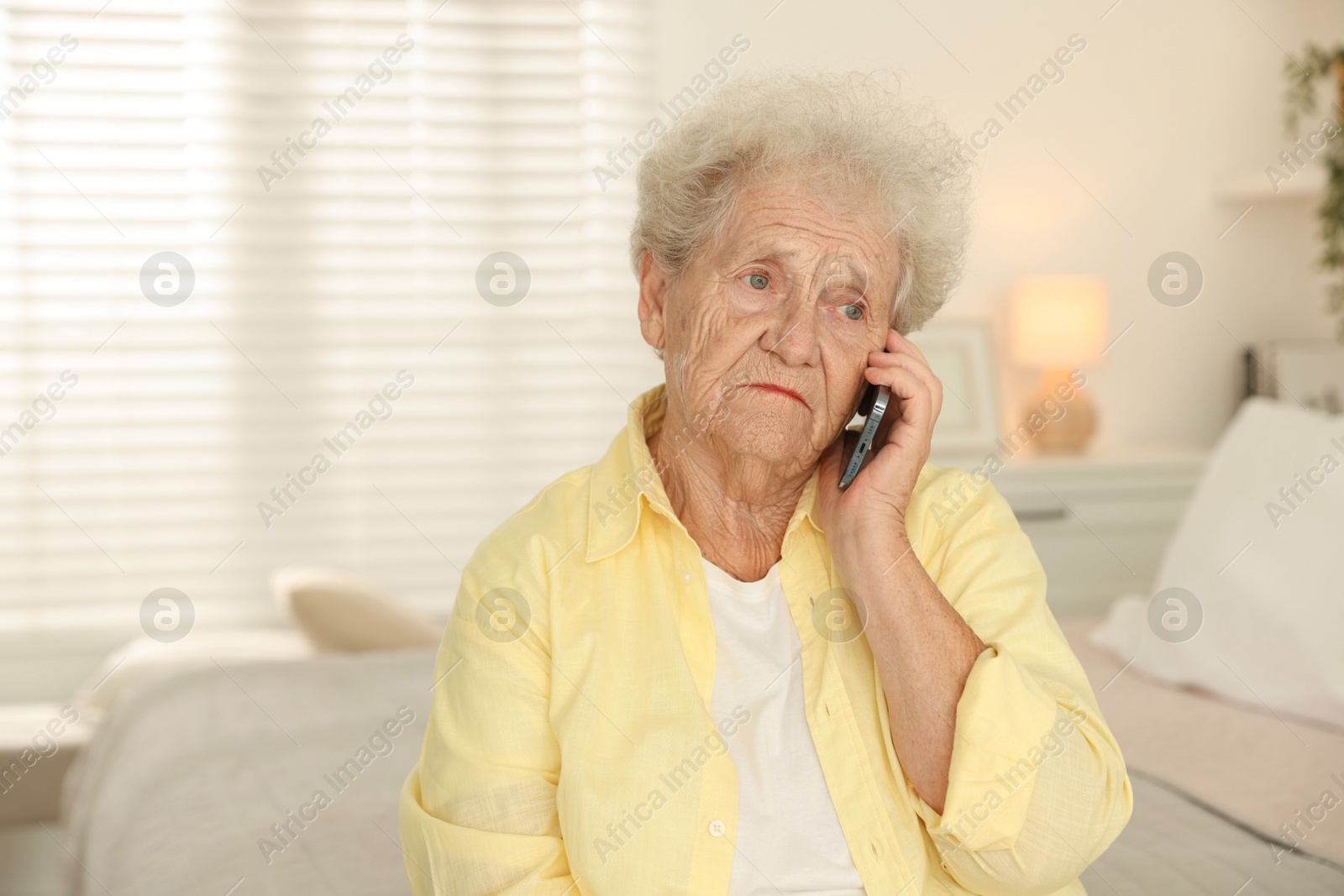 Photo of Senior woman talking on smartphone at home