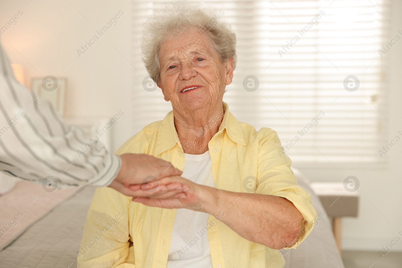 Photo of Senior woman holding hands with her granddaughter indoors