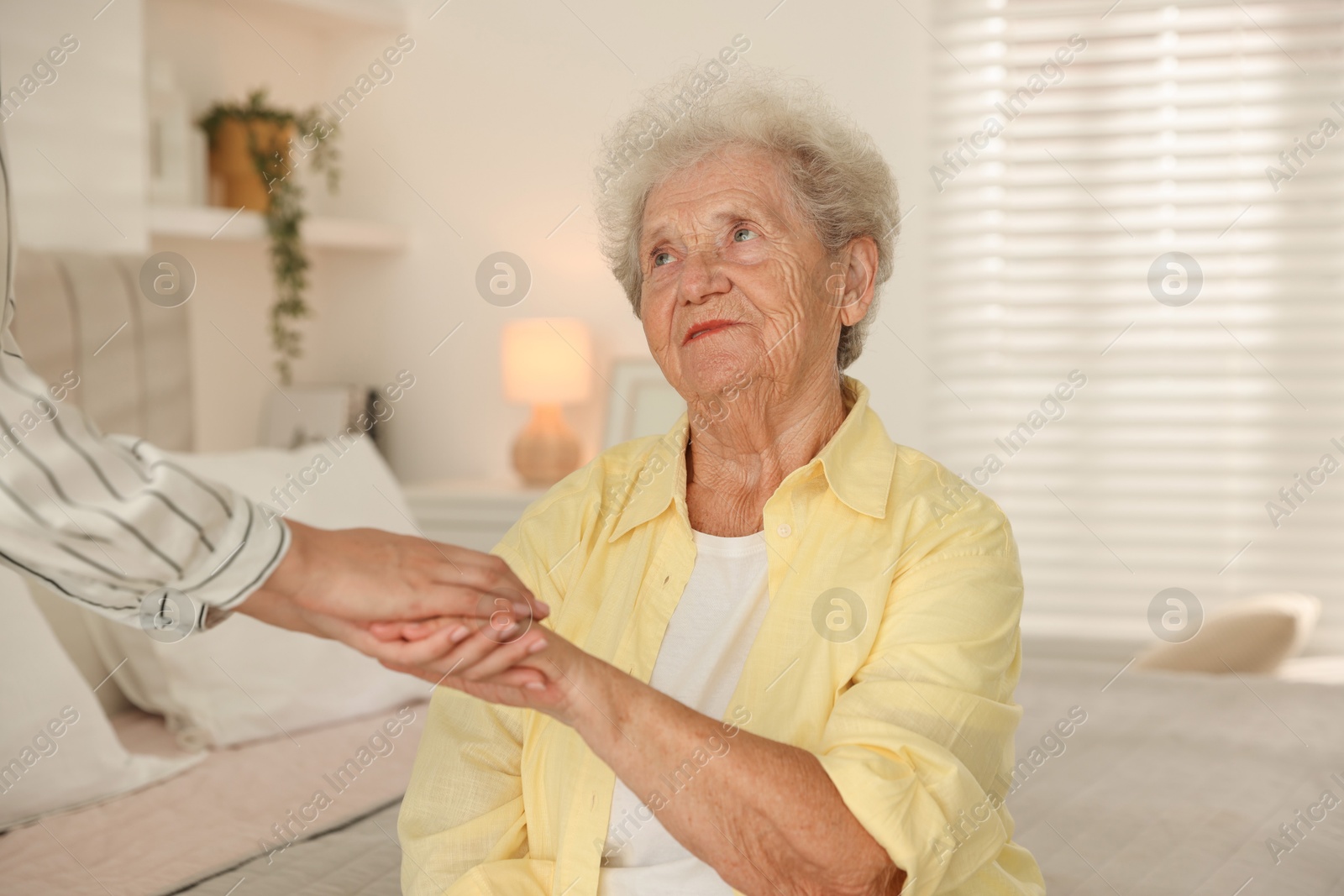 Photo of Senior woman holding hands with her granddaughter indoors