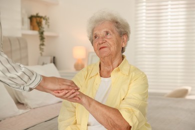 Photo of Senior woman holding hands with her granddaughter indoors