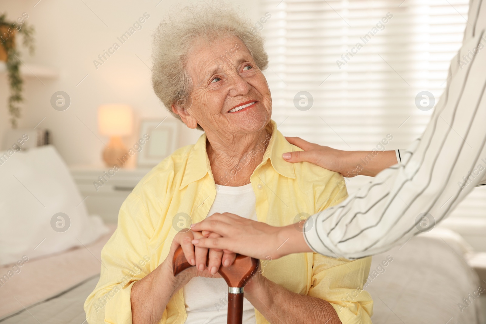 Photo of Senior woman with walking cane and her granddaughter at home