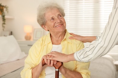 Senior woman with walking cane and her granddaughter at home