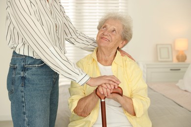 Senior woman with walking cane and her granddaughter at home