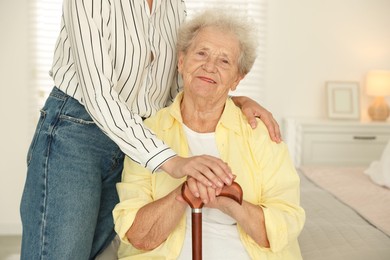 Senior woman with walking cane and her granddaughter at home