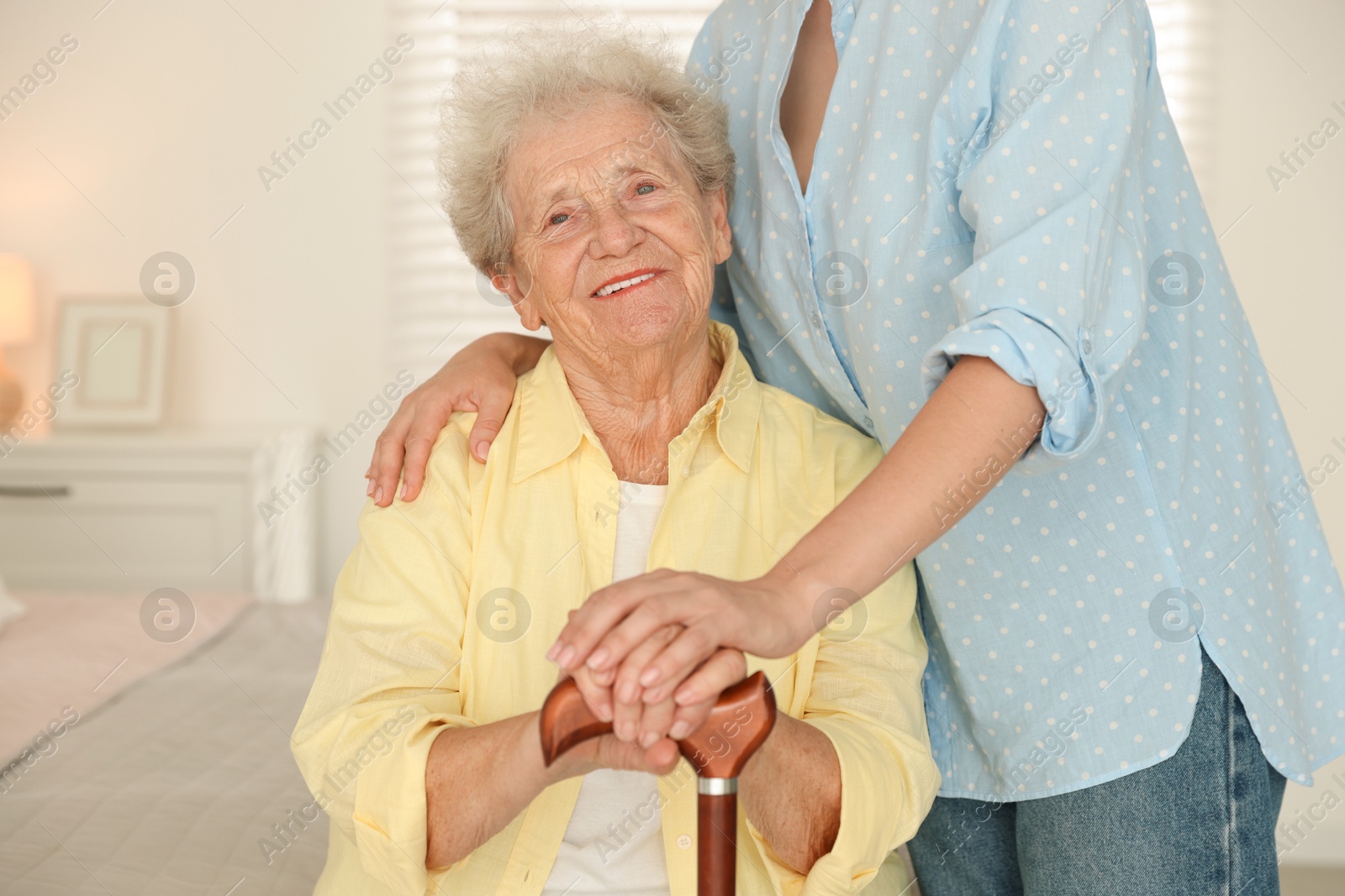 Photo of Senior woman with walking cane and her granddaughter at home