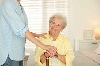 Photo of Senior woman with walking cane and her granddaughter at home