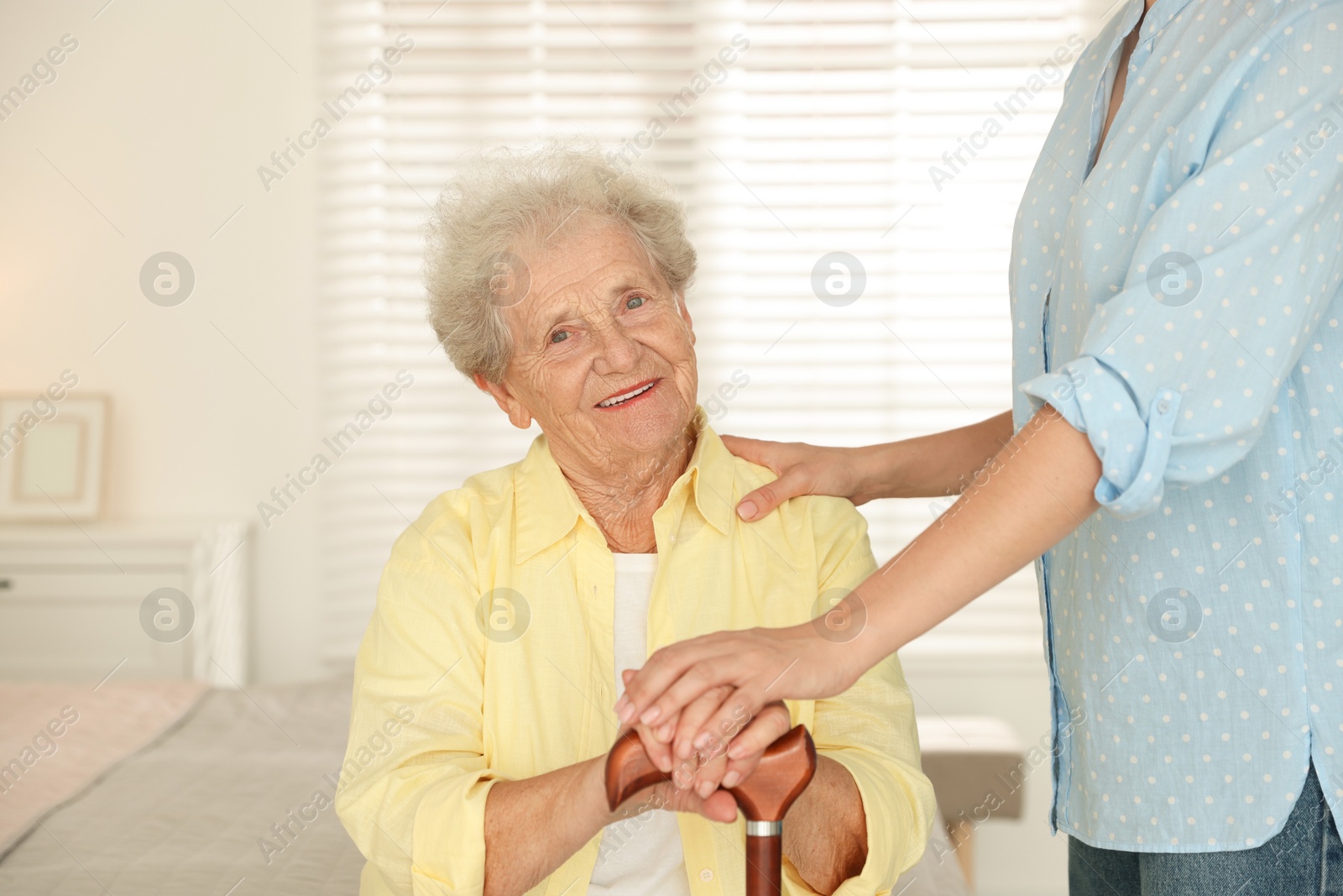 Photo of Senior woman with walking cane and her granddaughter at home