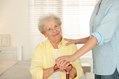 Photo of Senior woman with walking cane and her granddaughter at home