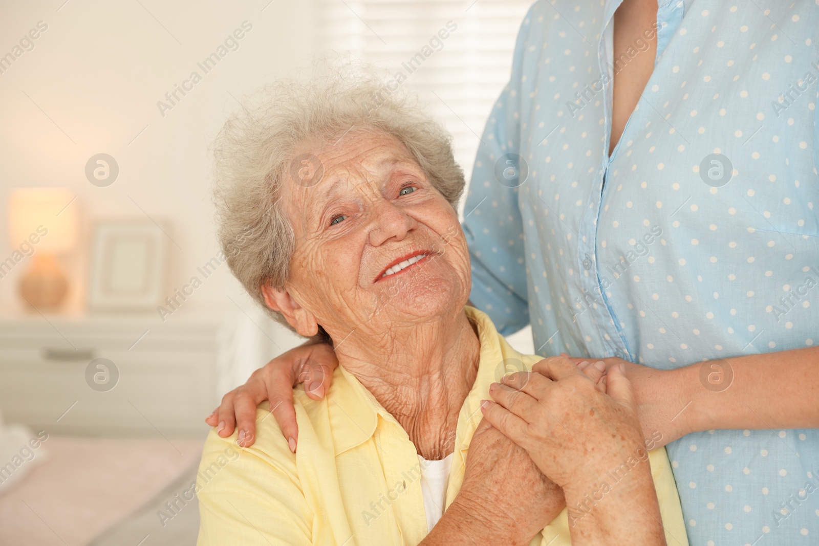 Photo of Senior woman holding hands with her granddaughter indoors