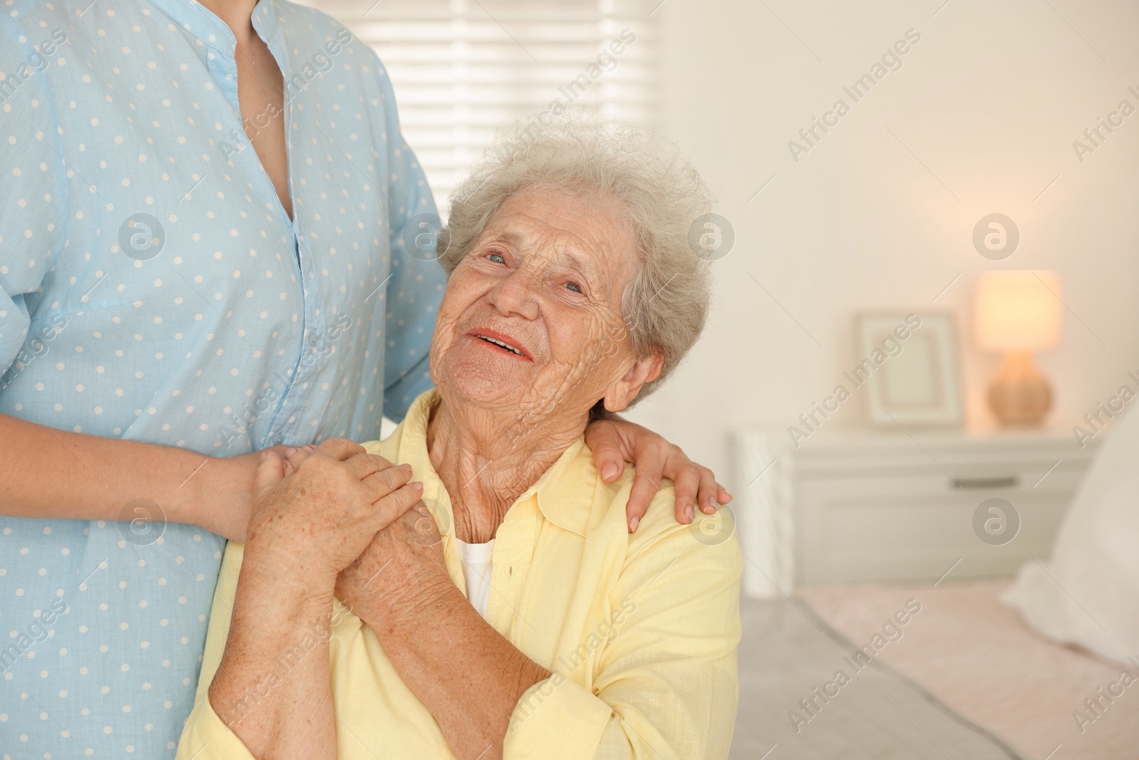 Photo of Senior woman holding hands with her granddaughter indoors