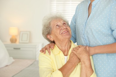 Photo of Senior woman holding hands with her granddaughter indoors