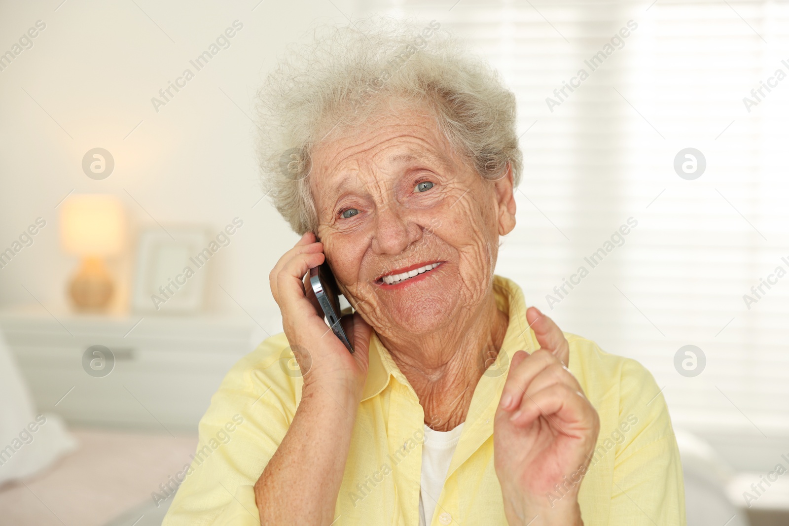 Photo of Smiling senior woman talking on smartphone indoors