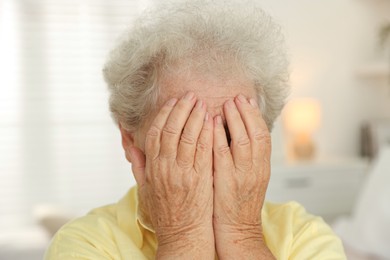 Photo of Senior woman closing her eyes with hands indoors, closeup