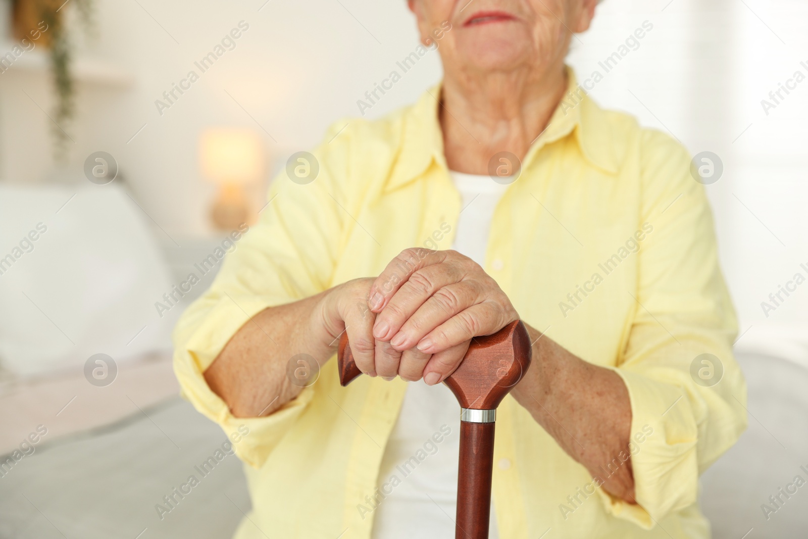 Photo of Senior woman with walking cane indoors, closeup