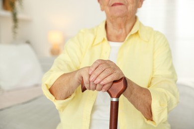 Senior woman with walking cane indoors, closeup