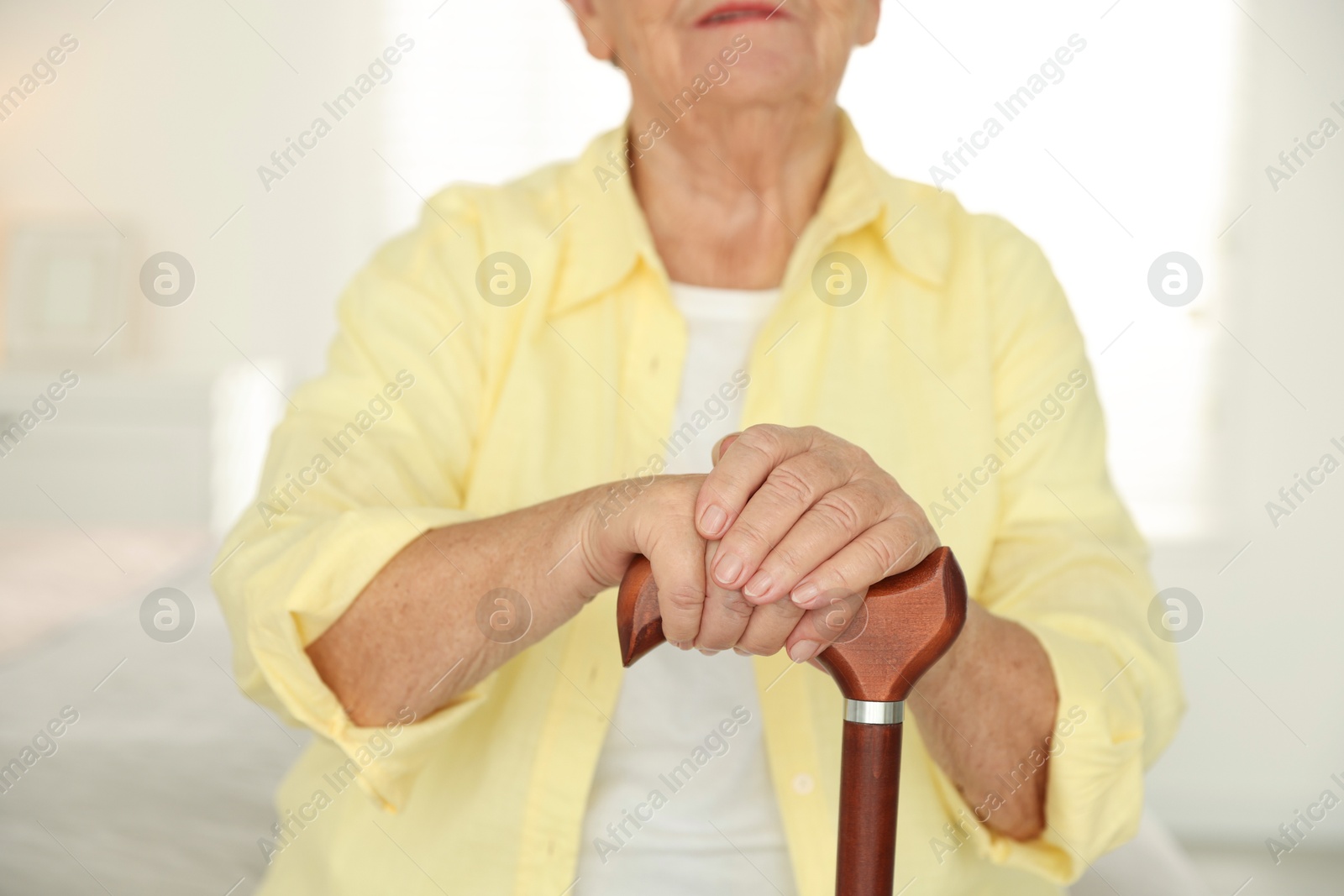 Photo of Senior woman with walking cane indoors, closeup