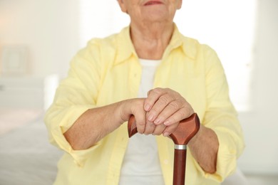 Senior woman with walking cane indoors, closeup