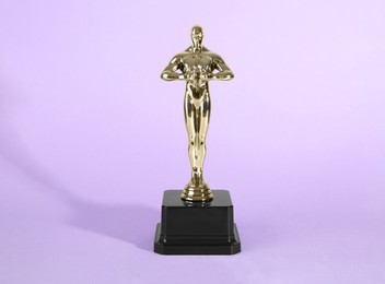 Photo of Golden trophy in shape of human figure on violet background