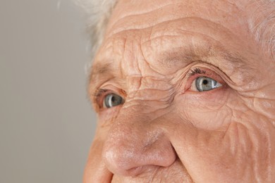 Photo of Senior woman with beautiful eyes on grey background, closeup