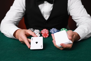 Professional croupier with playing cards at gambling table, closeup