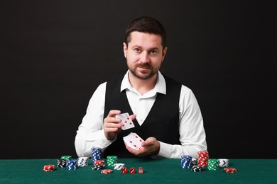 Professional croupier shuffling cards at gambling table against black background