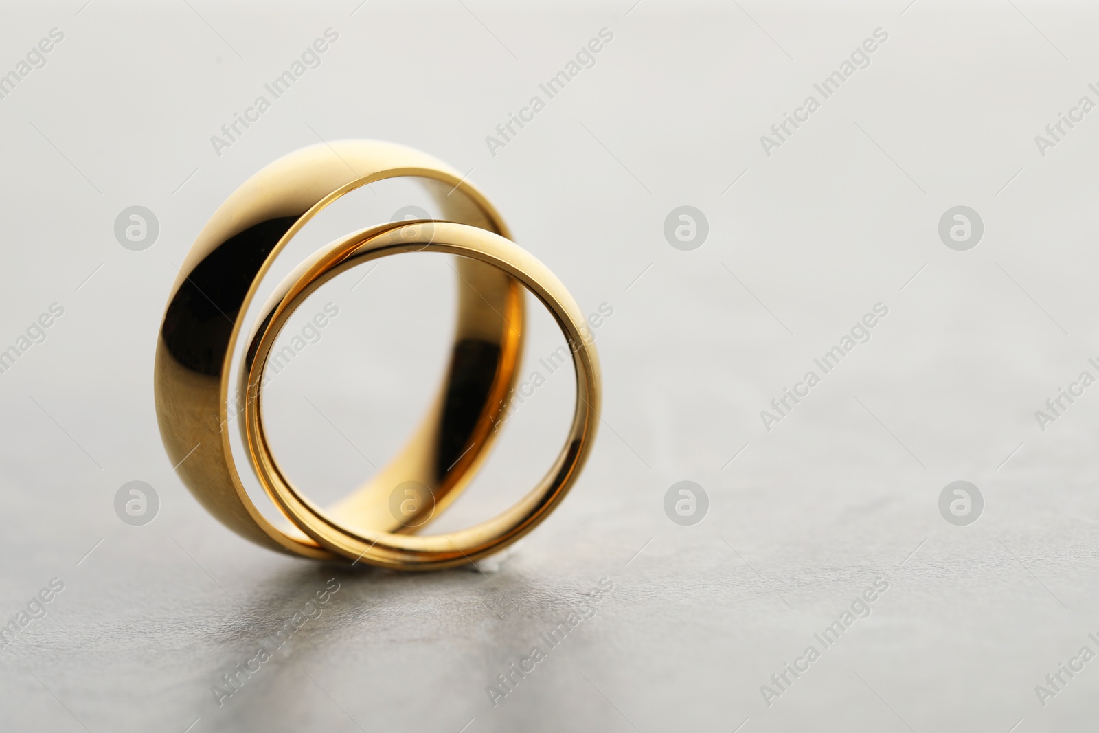 Photo of Beautiful golden wedding rings on gray background, closeup. Space for text