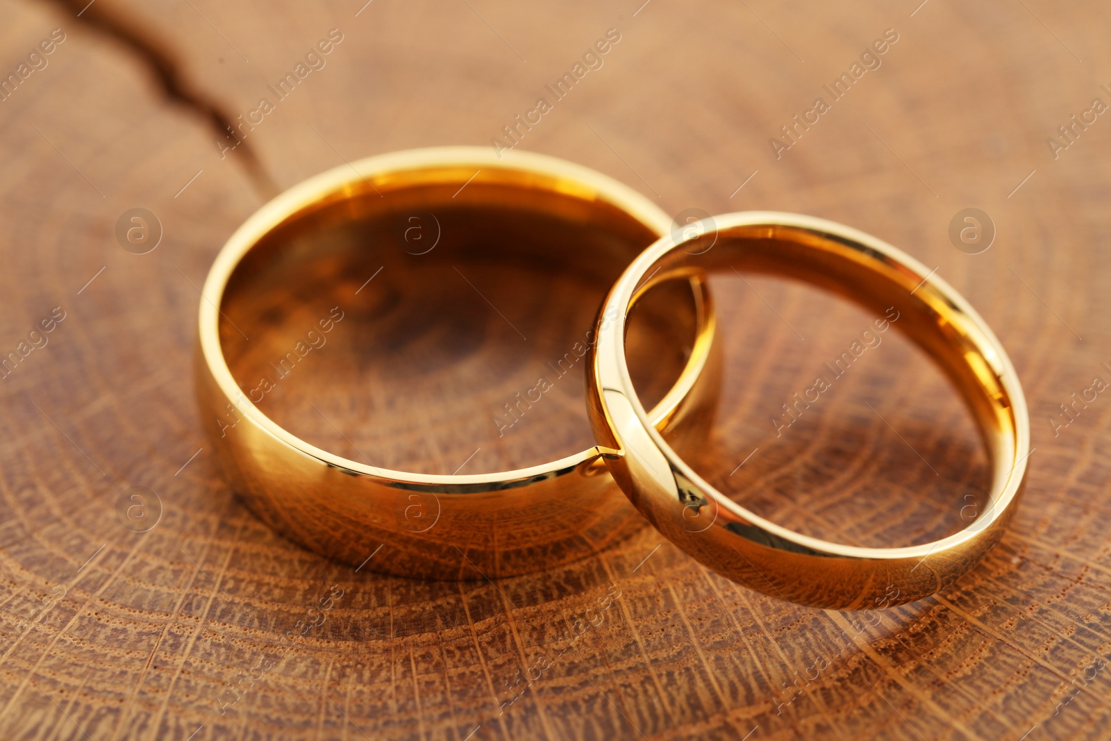 Photo of Beautiful golden wedding rings on wooden background, closeup