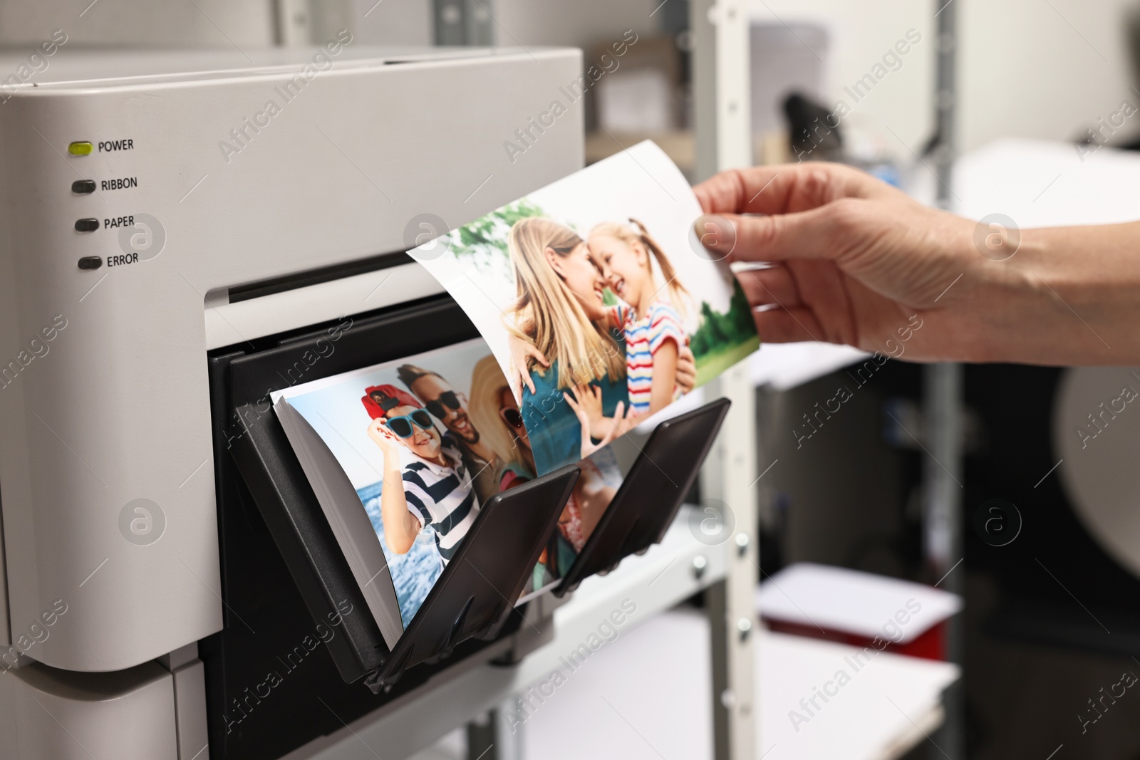 Photo of Woman with colorful photos near modern printer indoors, closeup