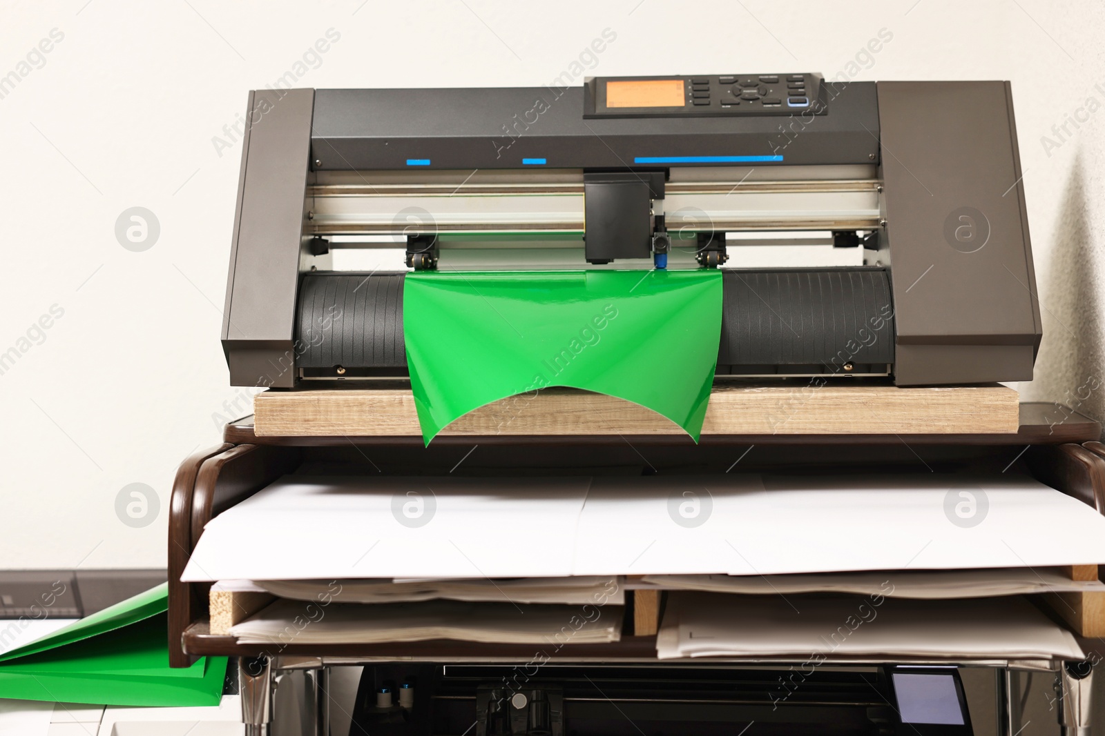 Photo of Modern cutting machine with green vinyl sheet indoors