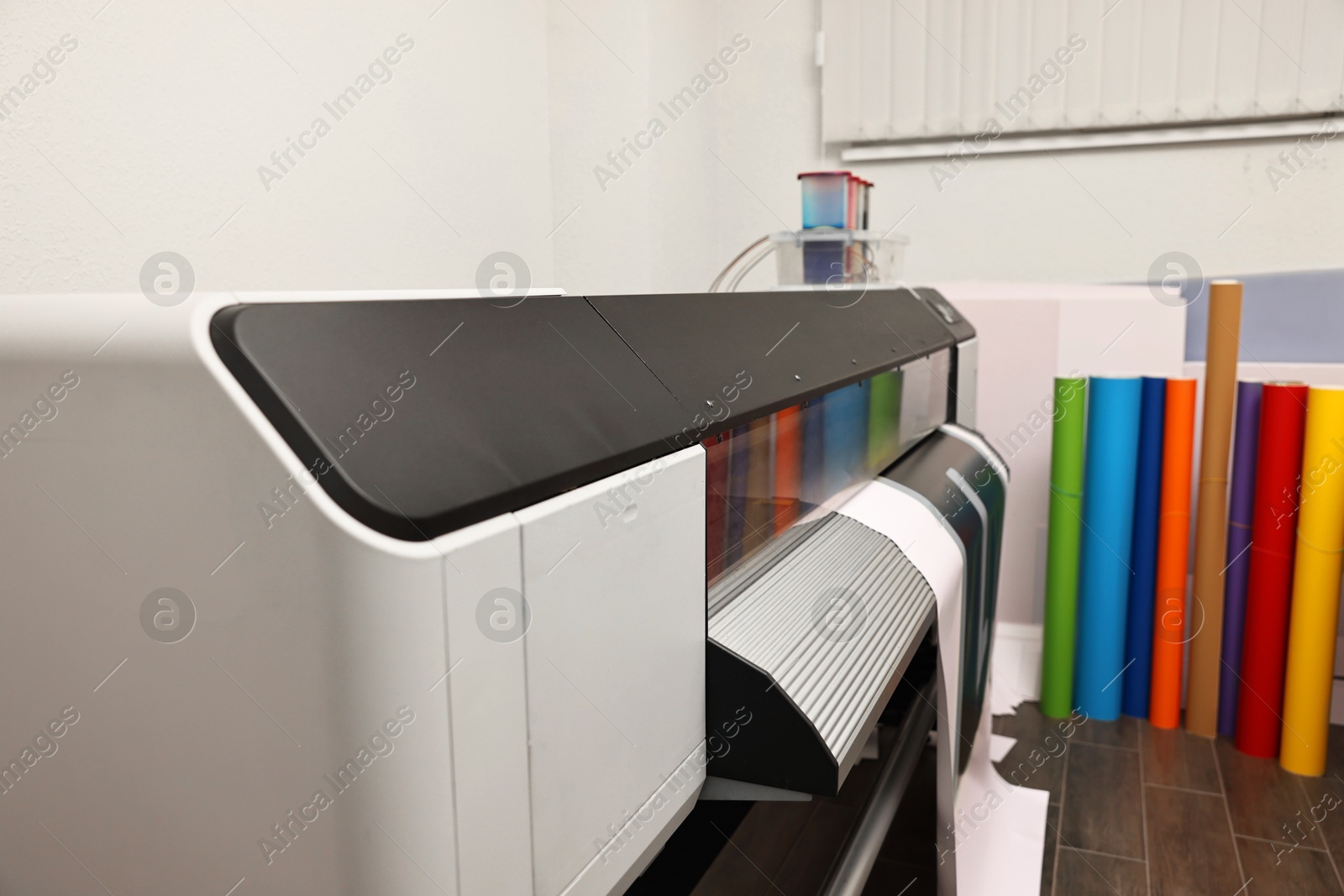 Photo of Wide-format printer with paper indoors, closeup. Printing house