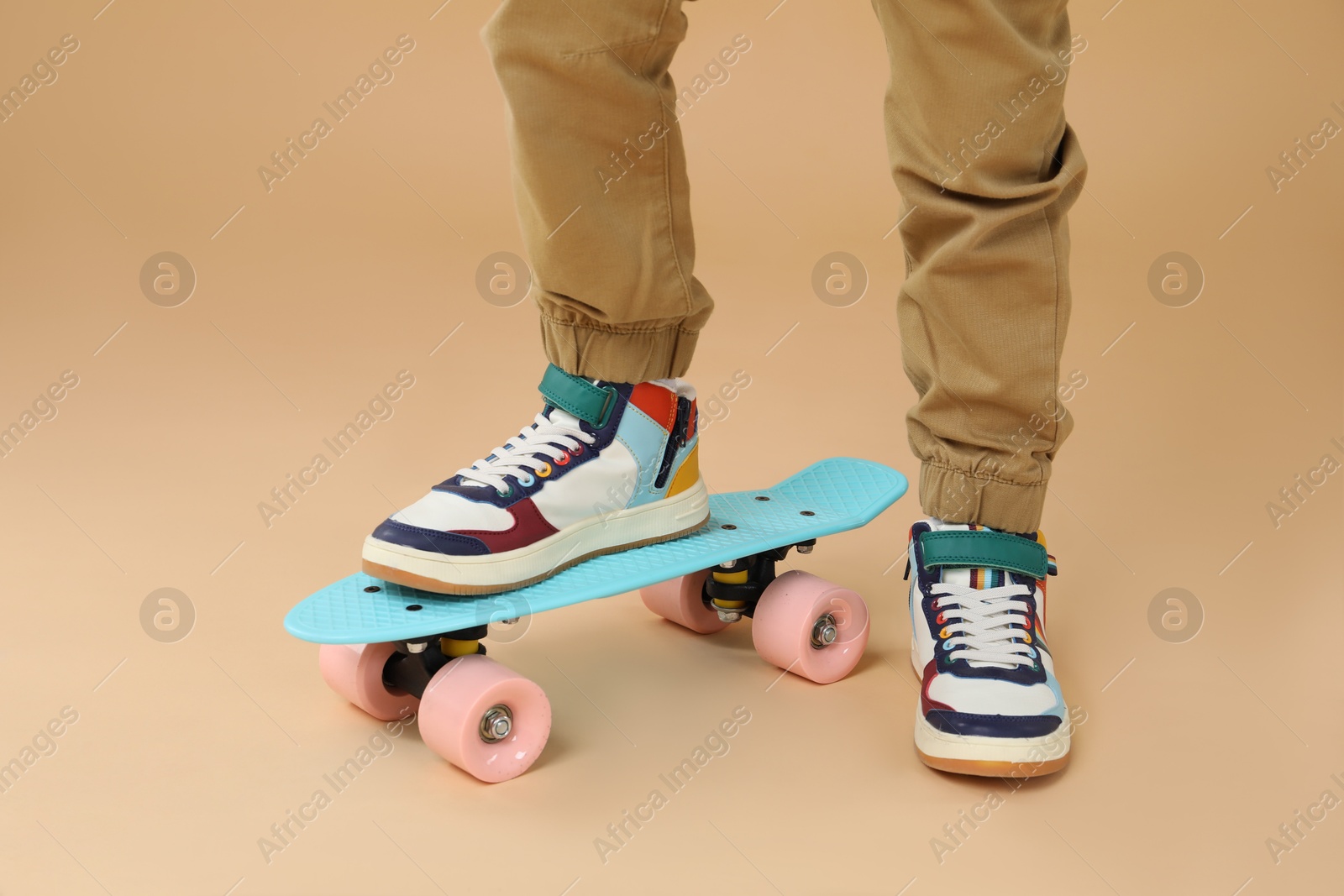 Photo of Little boy with skateboard on beige background, closeup