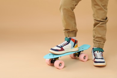 Photo of Little boy with skateboard on beige background, closeup. Space for text