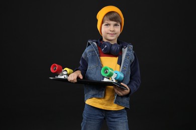 Little boy with skateboard on black background